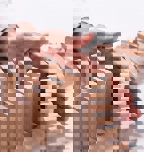 En hand som stoppar tre led av dominobrickor från att falla