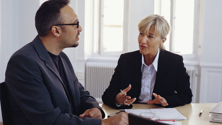 Kvinna och man samtalar i ett mötesrum.