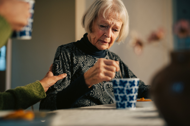 Kvinna som sitter vid köksbordet med en tekopp