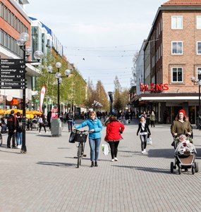 Bild på en gågata i Umeå centrum med människor som går, leder en cykel coh går med barnvagn.