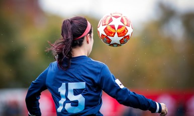 Ung kvinna bakifrån som spelar fotboll