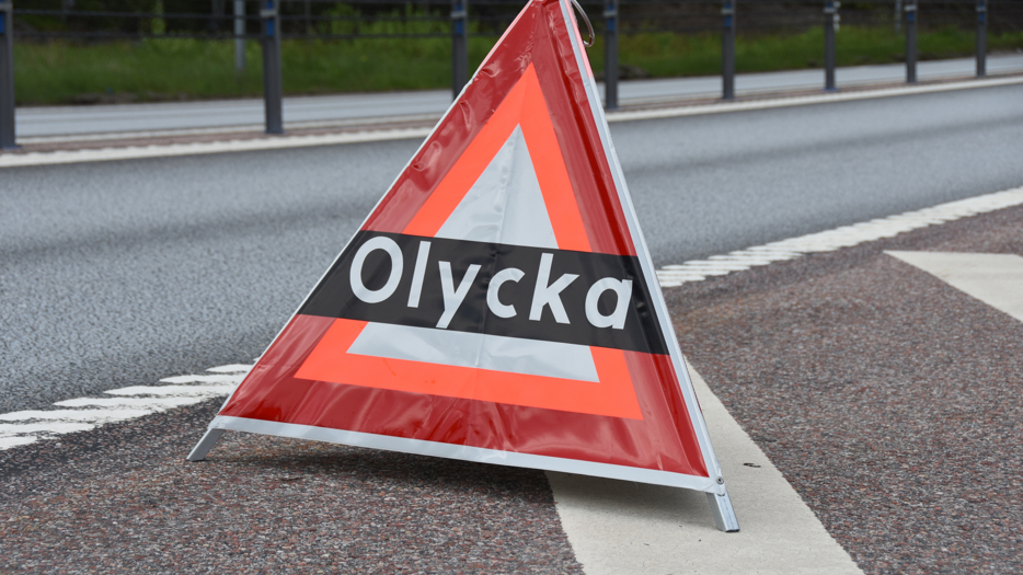 Varningstriangel med texten olycka placerad vid vägkant.