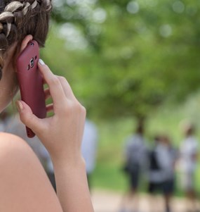 Flicka pratar i mobil i en park bortvänd från kameran