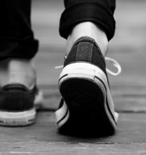 Persons sedd bakifrån, med fokus på hens skor.