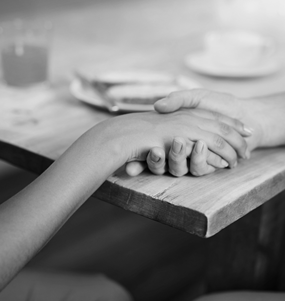 En hand som vilar i en annans hand på ett bord