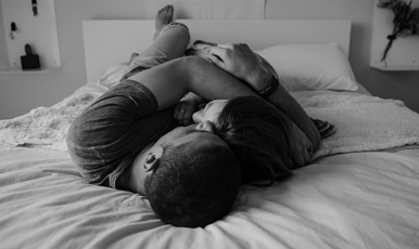 En ung man och kvinna som ligger omslingrande på en säng