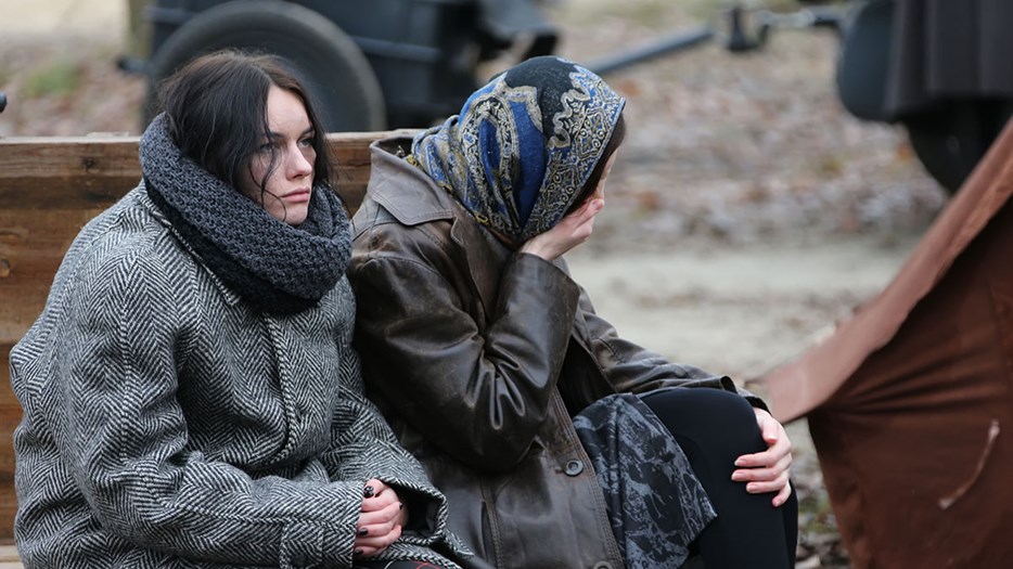 Två trötta kvinnor sitter utomhus i Ukraina.
