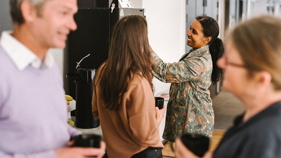 Fyra kollegor samtalar vid en kaffeautomat.