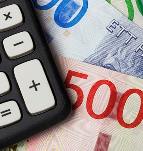 En miniräknare i närbild som ligger ovan på en bunt svenska sedlar