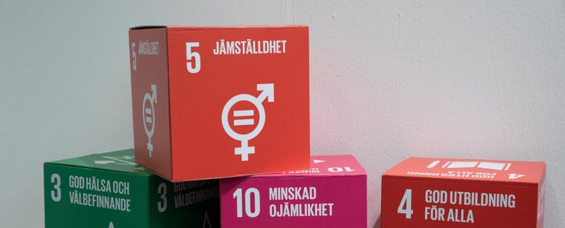 Foto på papperskuber staplade på varandra. Varje kub har ett nummer och en text på sig, t ex 10 Minskad ojämlikhet och 4 God utbildning för alla. Överst är 5 Jämställdhet.