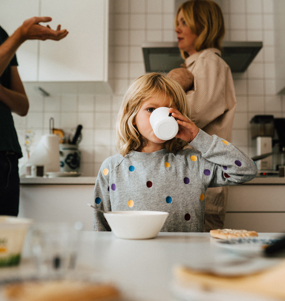 Barn äter frukost, vuxna pratar i bakgrunden.