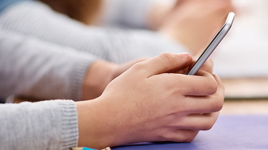 Två ungdomar chattar på mobiltelefoner.