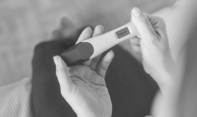 Händer som håller ett graviditetstest och det står "pregnant" på displayen