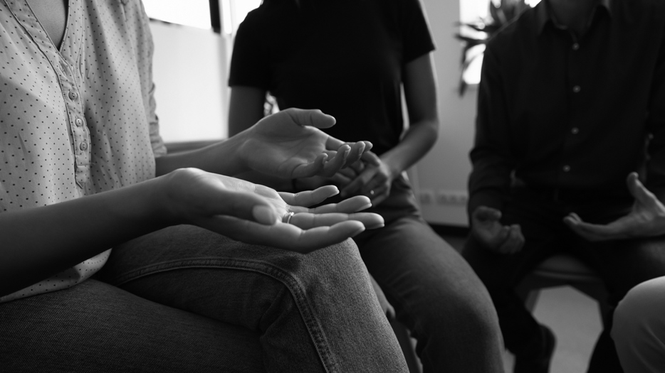 En grupp personer pratar med gestikulerande händer. Inga ansikten syns.