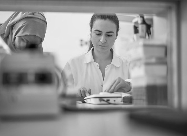 Två kvinnor i sjukvårdskläder arbetar i laboratorium.