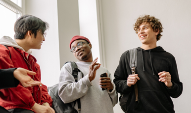 Tre unga killar samtalar med varandra i en ljus inomhusmiljö