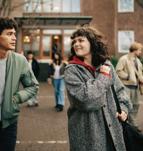 Två ungdomar som pratar med varandra på en skolgård.