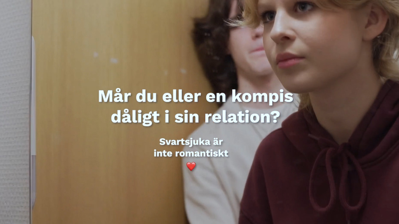 Från kampanjfilm för Svartsjuka är inte romantiskt. "Mår du eller en kompis dåligt i sin relation?" En tjej står framför en spegel på en skoltoalett och är obekväm. Hennes pojkvän står bakom henne och tittar på henne.