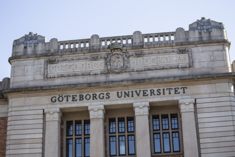 En av Göteborgs universitets pampiga, vita byggnader med texten "Göteborgs universitet" på ovanför stora fönster. 