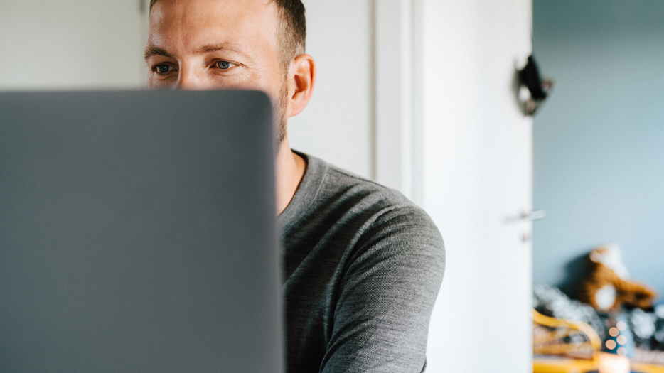 Man tittar på datorskärm. Ett barnrum syns i bakgrunden