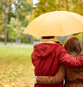 Man och kvinna bakifrån som håller om varandra under ett paraply