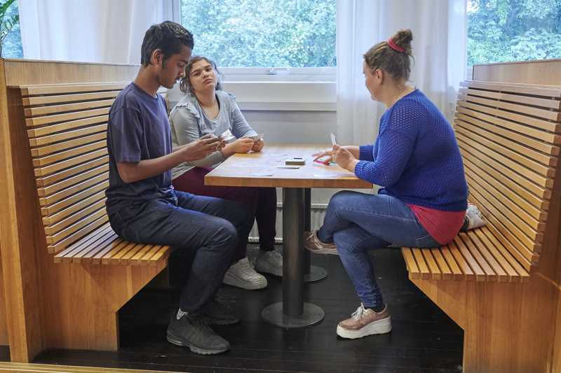 En vuxen spelar kort med två ungdomar